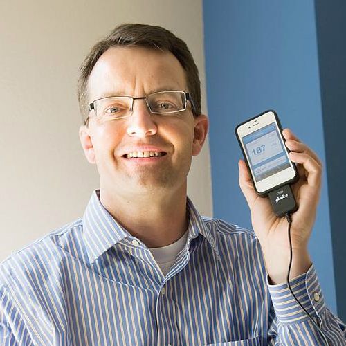 A photograph of Rick Altinger holding a smartphone.